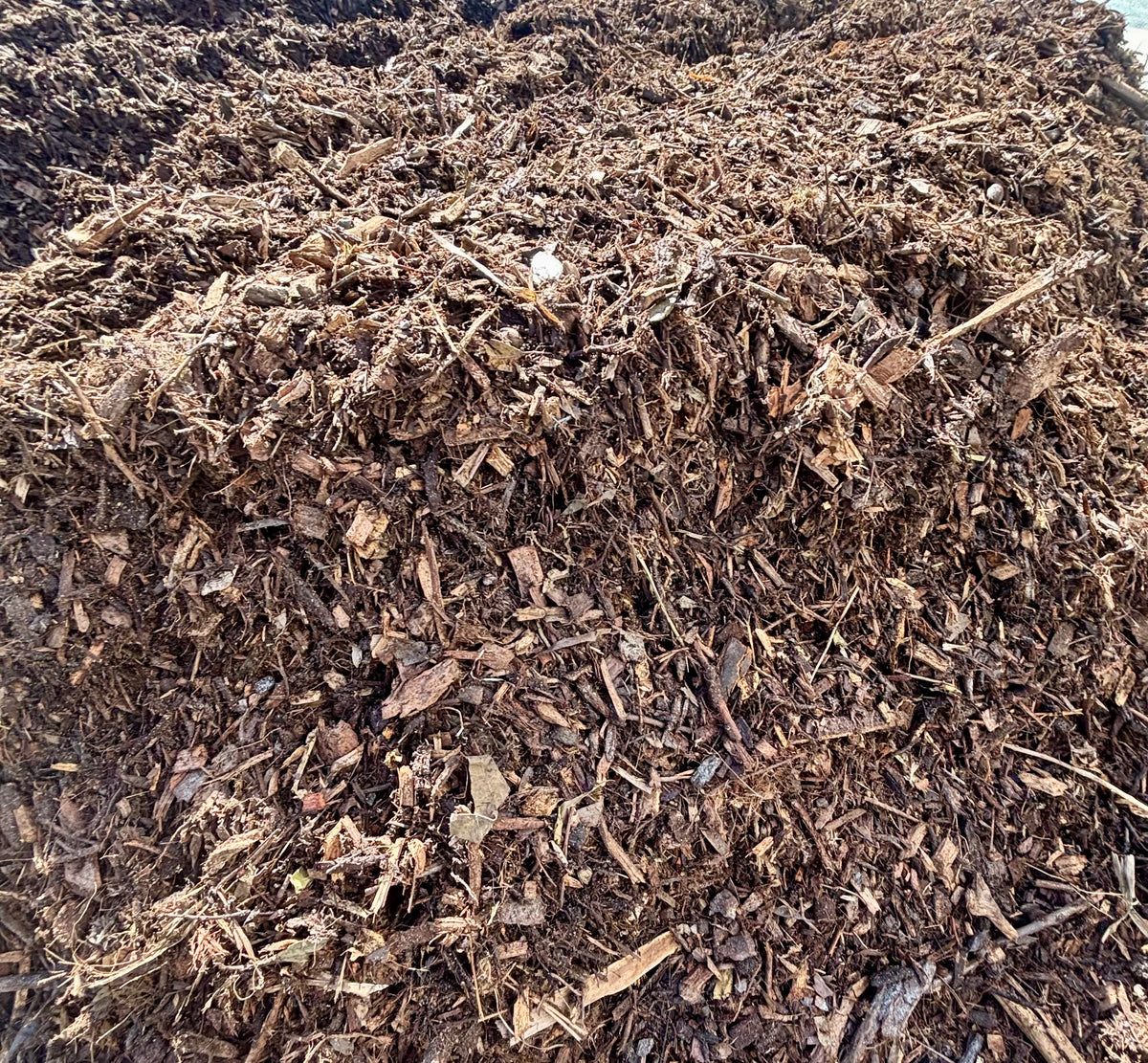 A large pile of dark brown wood chips, mulch, or compost material filling the frame.