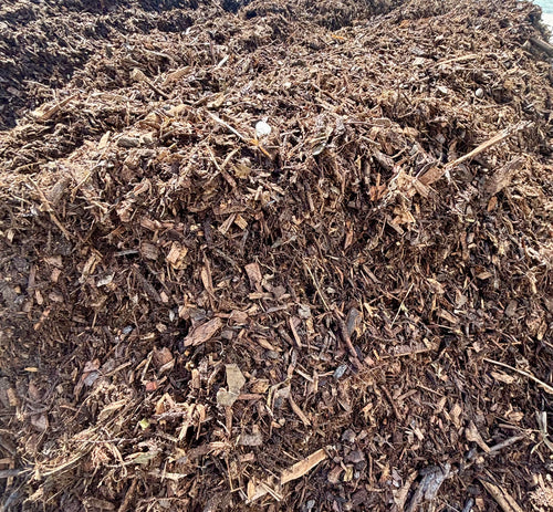 A large pile of dark brown wood chips, mulch, or compost material filling the frame.