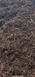A close-up view of dark brown wood chip mulch or shredded bark mulch filling the frame.