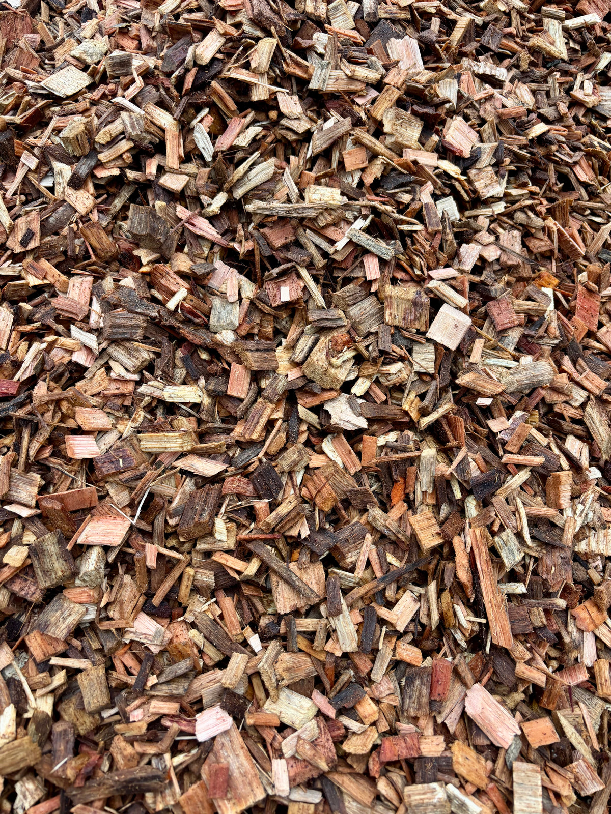 A close-up view of shredded wood mulch or bark chips in mixed natural brown, tan, and reddish tones.