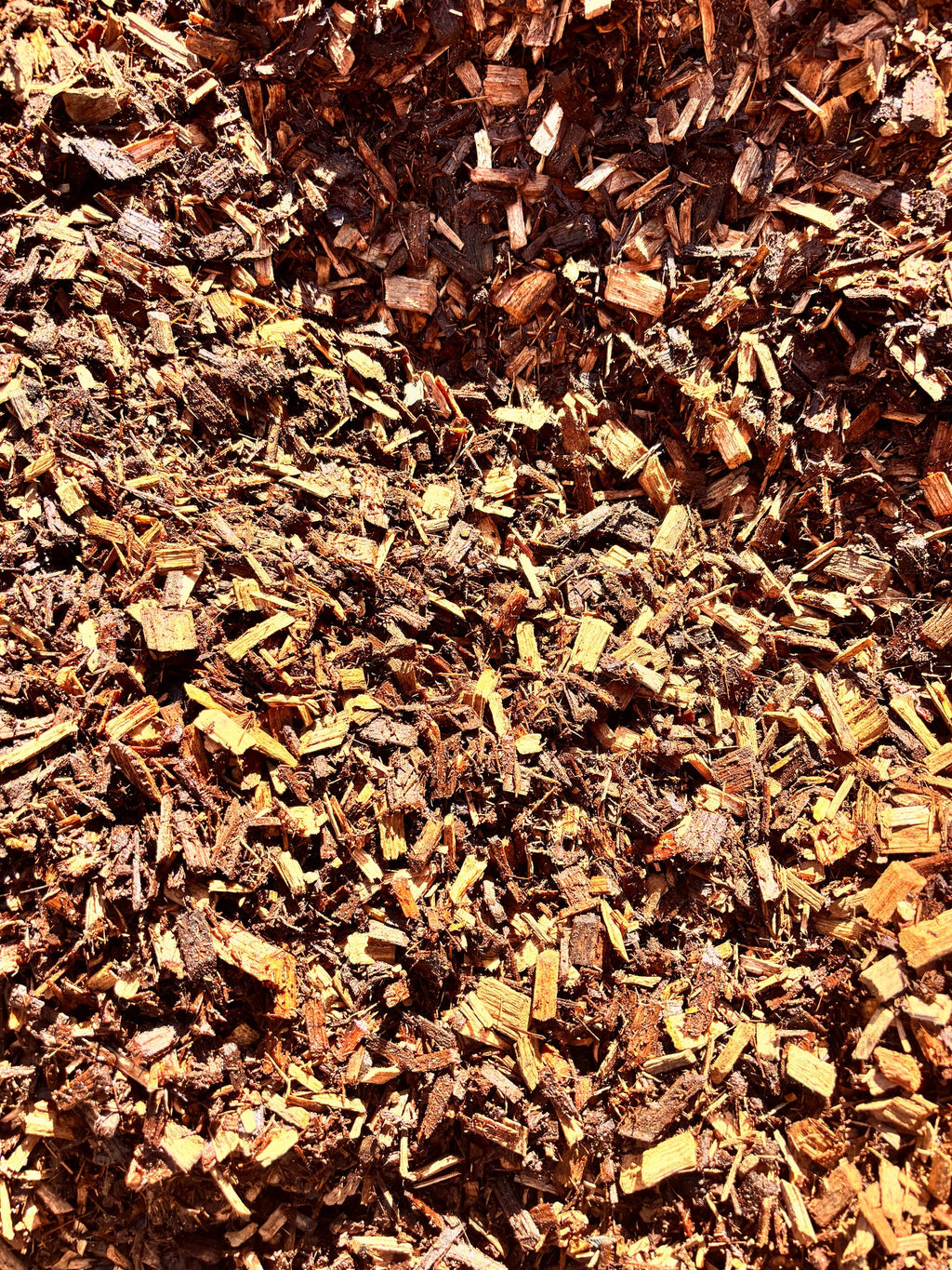 A close-up view of shredded wood mulch or bark chips in natural brown and tan tones, filling the entire frame.